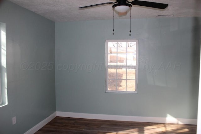 empty room with a textured ceiling, ceiling fan, dark wood finished floors, and baseboards