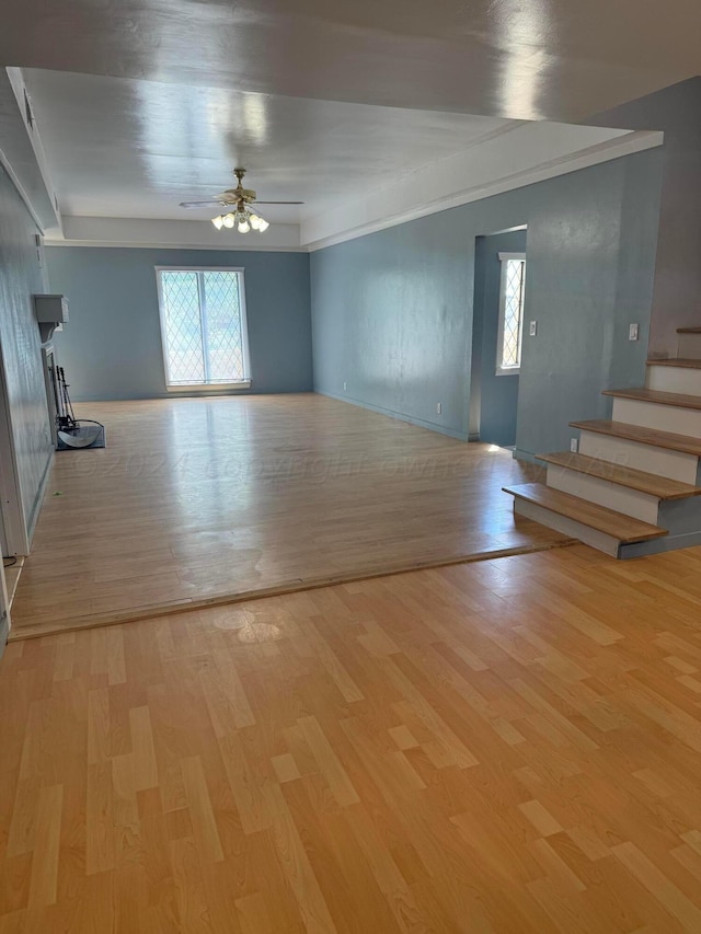 unfurnished living room featuring light wood-type flooring, ceiling fan, and crown molding