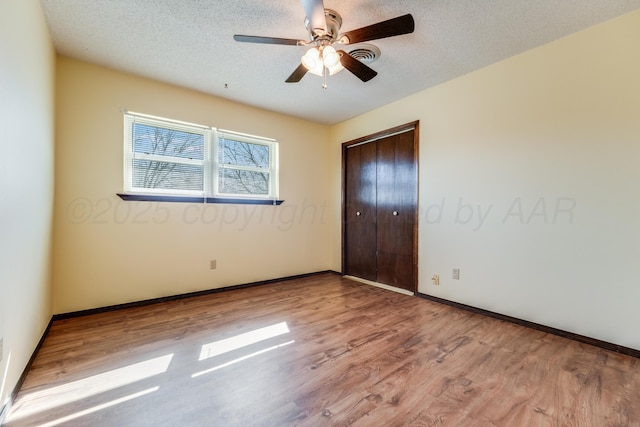 unfurnished bedroom featuring a closet, a textured ceiling, and wood finished floors