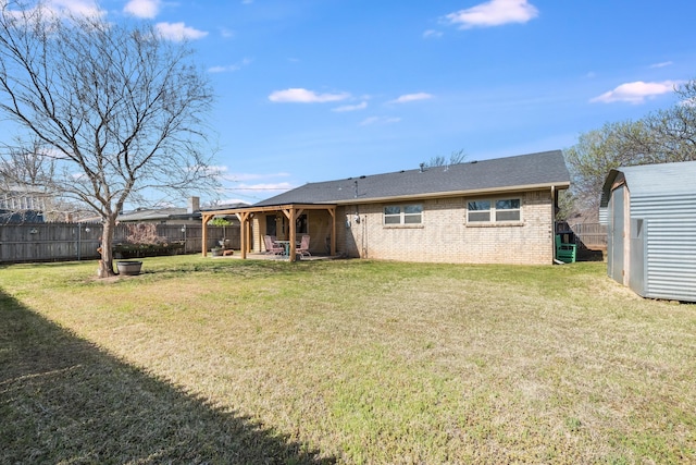 rear view of property featuring an outbuilding, a storage shed, a fenced backyard, a lawn, and brick siding