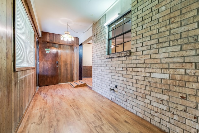 corridor with wood walls, wood finished floors, and brick wall