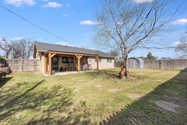 rear view of house with a patio, a yard, a fenced backyard, and a shed