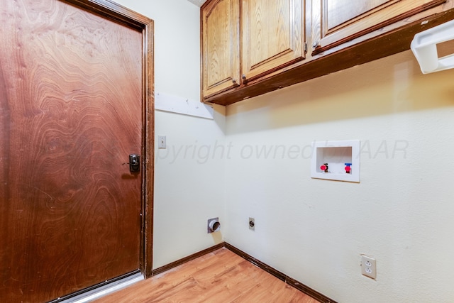 clothes washing area with baseboards, light wood-style floors, hookup for an electric dryer, cabinet space, and hookup for a washing machine