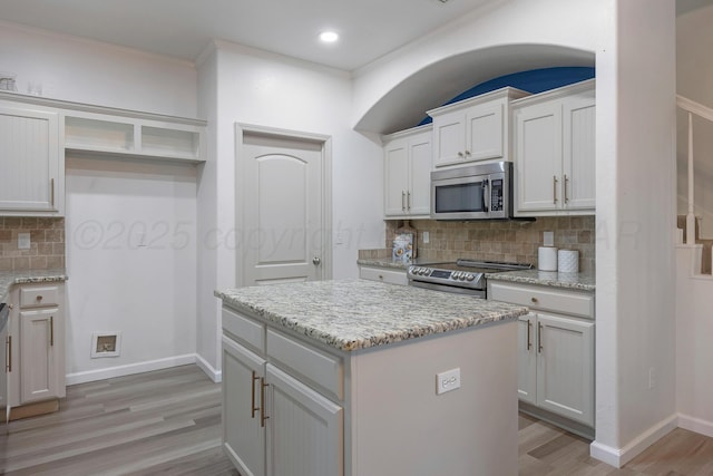 6809 Fanchun St, Amarillo, TX 79119 - kitchen featuring appliances with stainless steel finishes, light wood-style flooring, backsplash, crown molding, and light stone countertops