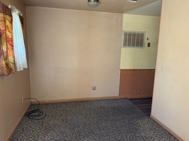 spare room with dark carpet