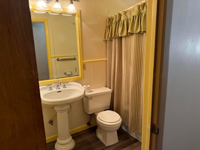 bathroom featuring tile walls, hardwood / wood-style floors, and toilet