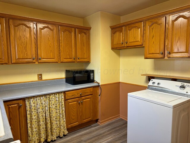 washroom featuring dark hardwood / wood-style flooring, washer / clothes dryer, and cabinets