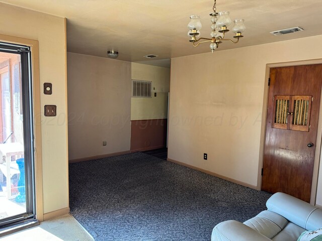 carpeted spare room featuring an inviting chandelier