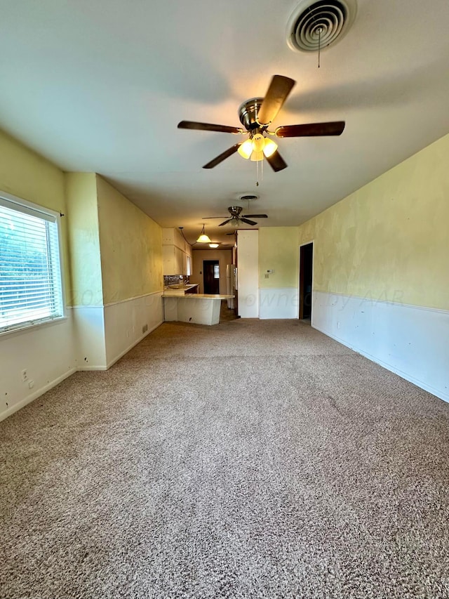 unfurnished living room with carpet and ceiling fan