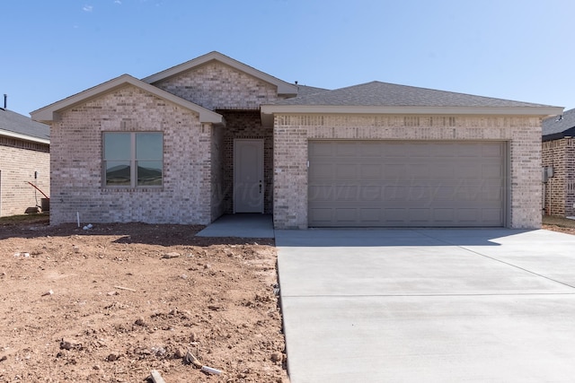 single story home featuring driveway, roof with shingles, a garage, and brick siding