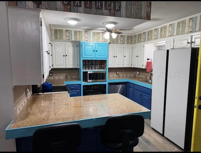 100 Bunavista St, Borger, TX 79007 - kitchen featuring blue cabinets, a breakfast bar, white cabinetry, appliances with stainless steel finishes, and kitchen peninsula