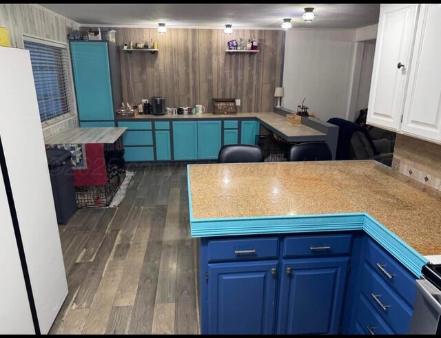 100 Bunavista St, Borger, TX 79007 - kitchen featuring blue cabinetry, white cabinetry, white refrigerator, and dark hardwood / wood-style floors