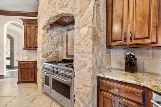 kitchen featuring light stone counters, double oven range, decorative backsplash, and light tile patterned floors