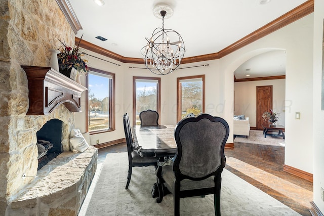 dining space featuring ornamental molding, a stone fireplace, and an inviting chandelier