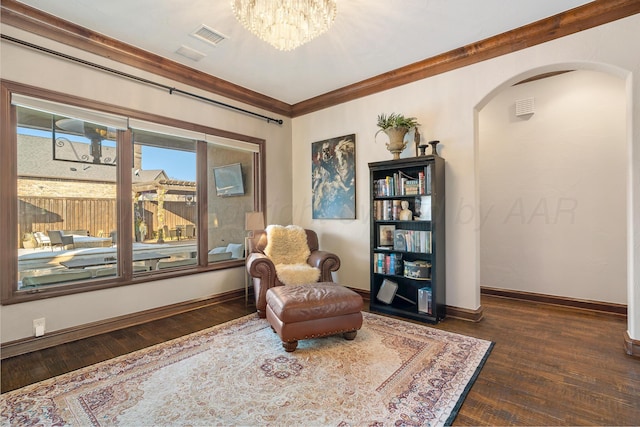 sitting room featuring ornamental molding, dark wood-type flooring, and an inviting chandelier