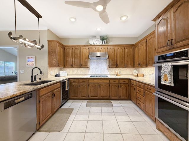 8 Glenbrook Dr, Borger, TX 79007 - kitchen with appliances with stainless steel finishes, under cabinet range hood, beverage cooler, decorative backsplash, and brown cabinetry