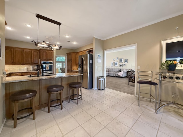 8 Glenbrook Dr, Borger, TX 79007 - kitchen with appliances with stainless steel finishes, a breakfast bar area, light stone counters, hanging light fixtures, and recessed lighting