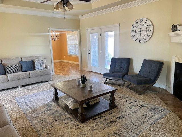 living room featuring ceiling fan with notable chandelier and crown molding