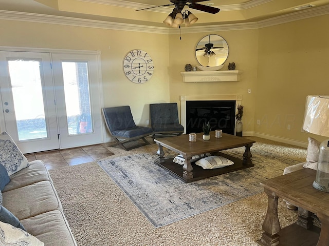 living room featuring ceiling fan, ornamental molding, light tile patterned floors, and a tray ceiling