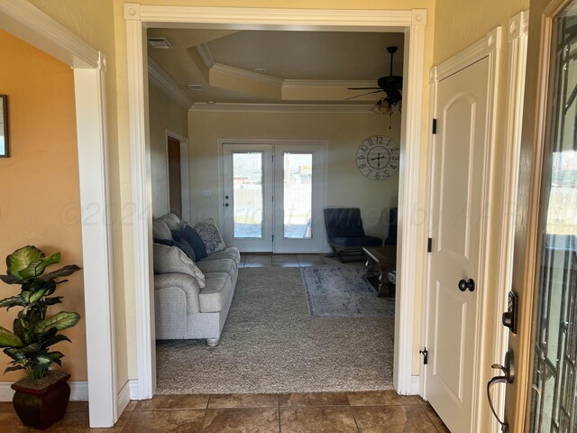 living room featuring ceiling fan, french doors, a tray ceiling, dark carpet, and ornamental molding