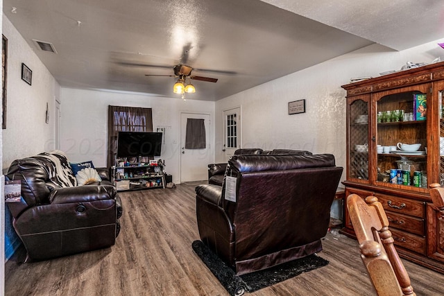 living room with a textured ceiling, hardwood / wood-style flooring, and ceiling fan