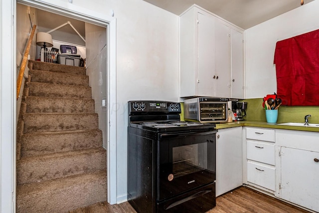 kitchen featuring white cabinets, hardwood / wood-style flooring, black range with electric cooktop, and sink