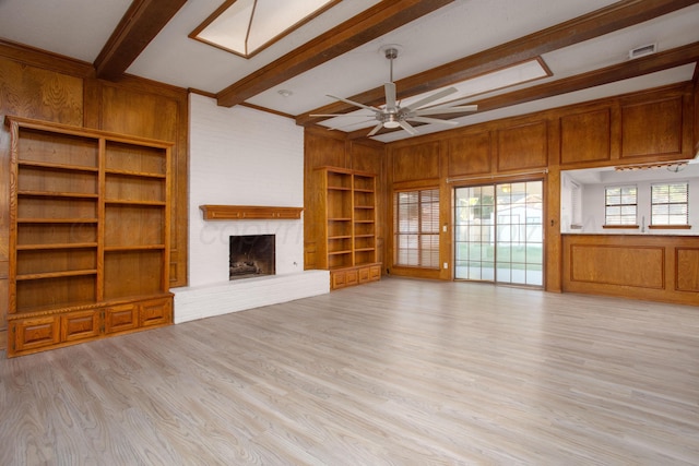 7408 Sleepy Hollow Blvd, Amarillo, TX 79121 - unfurnished living room featuring beamed ceiling, built in shelves, wood walls, a brick fireplace, and a ceiling fan