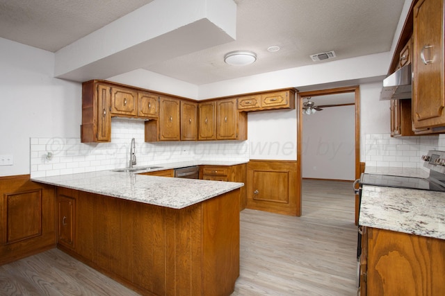 7408 Sleepy Hollow Blvd, Amarillo, TX 79121 - kitchen with under cabinet range hood, a peninsula, stainless steel range with electric stovetop, a sink, and brown cabinets