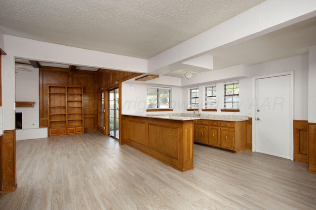 7408 Sleepy Hollow Blvd, Amarillo, TX 79121 - kitchen with brown cabinetry, light wood-style flooring, light countertops, wood walls, and a textured ceiling