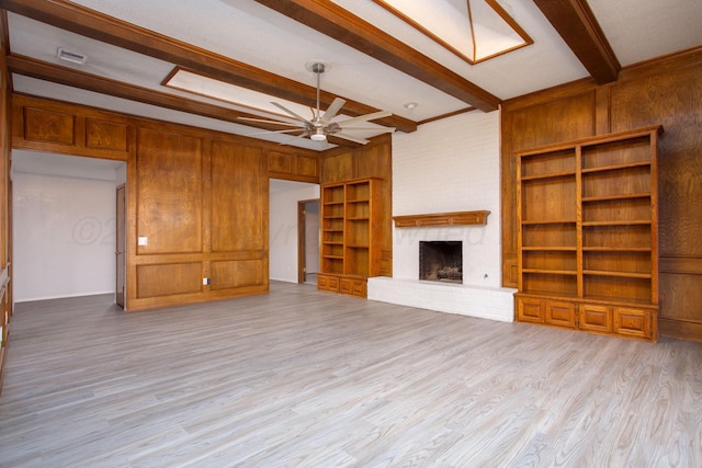 7408 Sleepy Hollow Blvd, Amarillo, TX 79121 - unfurnished living room featuring beamed ceiling, a brick fireplace, wood finished floors, a ceiling fan, and wooden walls