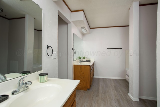 7408 Sleepy Hollow Blvd, Amarillo, TX 79121 - bathroom featuring wood finished floors, crown molding, two vanities, baseboards, and a textured ceiling
