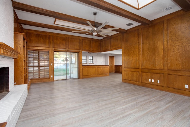 7408 Sleepy Hollow Blvd, Amarillo, TX 79121 - unfurnished living room featuring ceiling fan, light wood-style floors, beamed ceiling, a brick fireplace, and a decorative wall