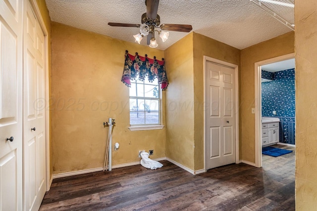 2723 County Road O, Friona, TX 79035 - unfurnished bedroom with dark wood-type flooring, baseboards, a textured ceiling, connected bathroom, and ceiling fan