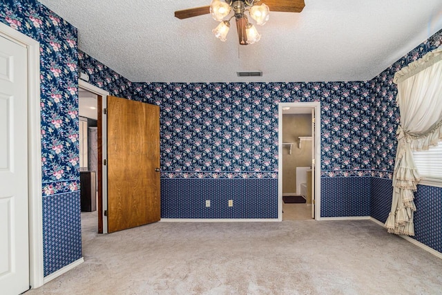 2723 County Road O, Friona, TX 79035 - unfurnished bedroom with wallpapered walls, carpet, a textured ceiling, a ceiling fan, and baseboards