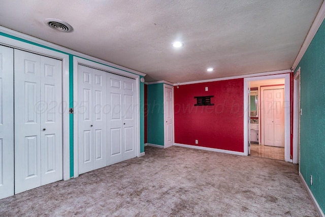 402 Beach Ave, Friona, TX 79035 - unfurnished bedroom featuring carpet floors, a textured ceiling, two closets, baseboards, and visible vents