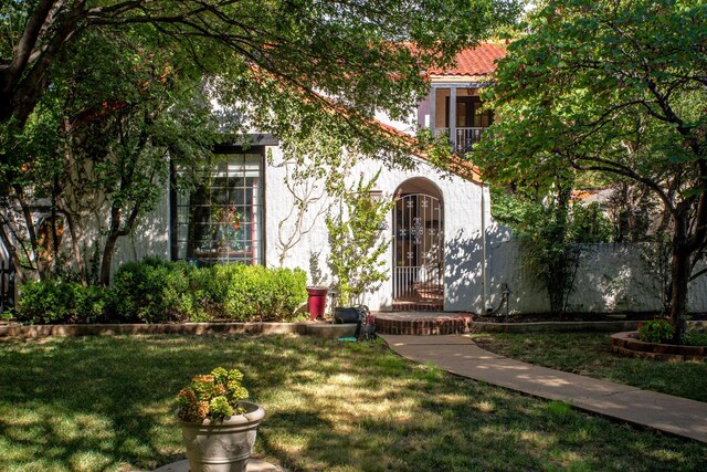 entrance to property featuring a yard, a tiled roof, and stucco siding