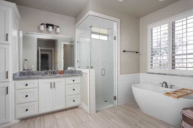 bathroom featuring vanity, tile walls, plenty of natural light, and independent shower and bath