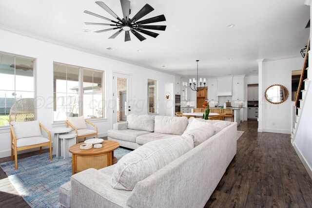 living room with ornamental molding, ceiling fan with notable chandelier, and dark hardwood / wood-style floors