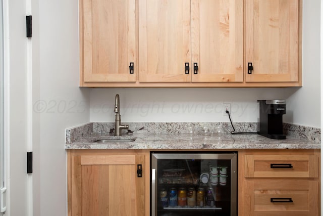 bar featuring sink, light stone countertops, beverage cooler, and light brown cabinetry