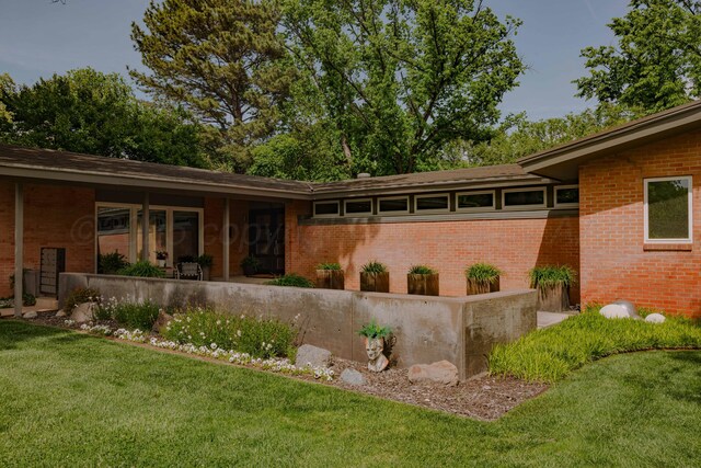 back of house featuring a yard and brick siding