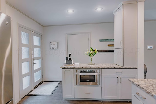 kitchen with appliances with stainless steel finishes, crown molding, light stone countertops, dark wood-style floors, and french doors