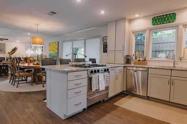 kitchen featuring appliances with stainless steel finishes, a sink, a peninsula, dark wood finished floors, and recessed lighting