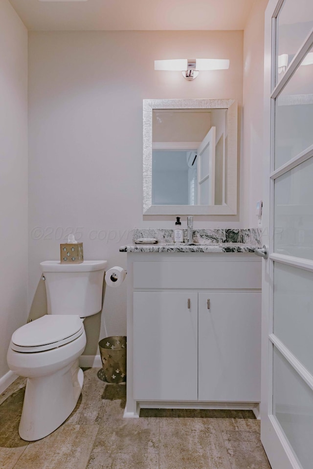 bathroom featuring toilet, vanity, and baseboards