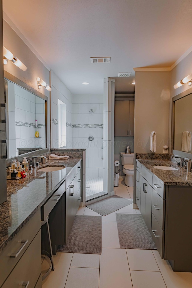 bathroom featuring a walk in shower, tile patterned floors, toilet, two vanities, and ornamental molding