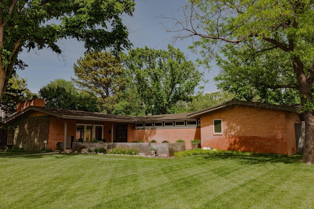 back of property with brick siding, a yard, and a chimney
