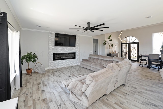 living room featuring ceiling fan, crown molding, a fireplace, and light hardwood / wood-style flooring