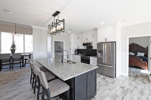 kitchen featuring light stone counters, stainless steel appliances, sink, white cabinets, and hanging light fixtures