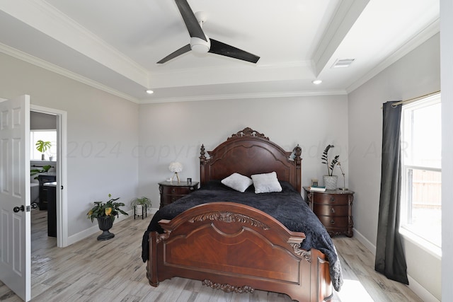 bedroom featuring ceiling fan, multiple windows, crown molding, and a tray ceiling