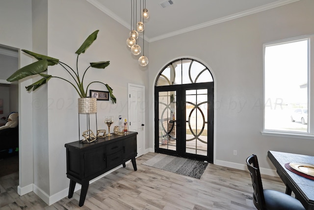 entryway featuring ornamental molding, light hardwood / wood-style flooring, a wealth of natural light, and french doors