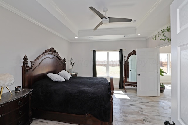 bedroom featuring ceiling fan, light hardwood / wood-style floors, a raised ceiling, and ornamental molding